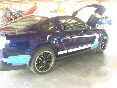 2007 Ford Mustang - A blue 2007 Ford Mustang with white racing stripes is parked with its hood open.