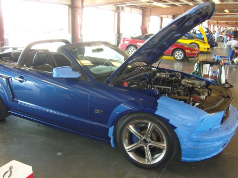 2007 Ford Mustang - A blue 2007 Ford Mustang convertible is shown with its hood open and front end taped, possibly for painting or repair.