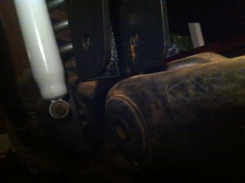 1990 Ford Bronco - Close-up of a white shock absorber and dark metal suspension components, possibly from a truck or SUV.
