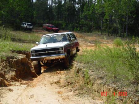 1991 Ford Bronco - This SUV navigates a challenging off-road trail, with other vehicles visible in the distance.