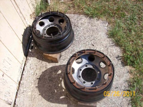 1982 Ford F-100 - Two truck wheels are shown outdoors, resting on a concrete surface near a wooden wall.