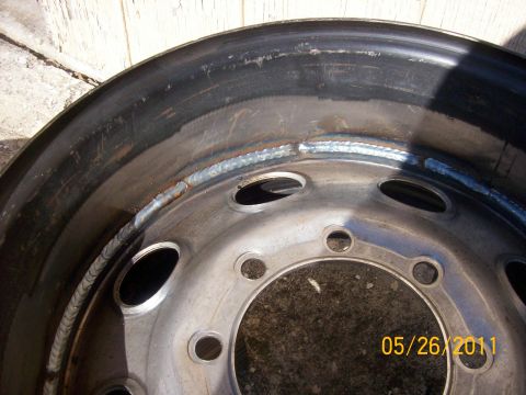 1982 Ford F-100 - A steel wheel rim shows evidence of repair work with visible welds along its circumference.
