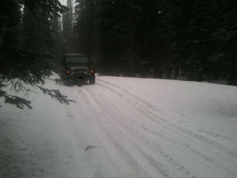 2005 Jeep Wrangler - A 2005 Jeep Wrangler navigates a snowy path in a wooded area.