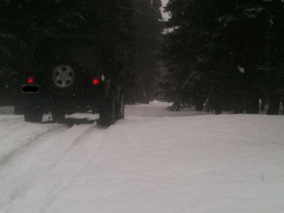 Jeep Wrangler rear view in snow, spare tire visible on back