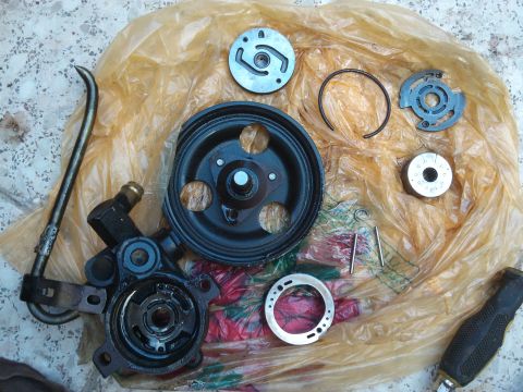 1998 Ford Crown Victoria - A disassembled power steering pump and its components are spread out on a plastic bag, with a SuperMotors logo visible.