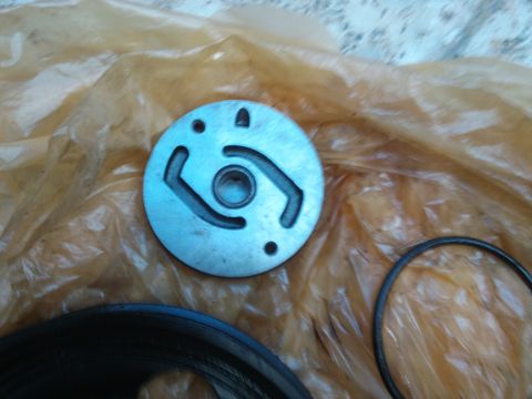 1998 Ford Crown Victoria - Close-up of a metal power steering pump plate and O-ring, likely a replacement part.