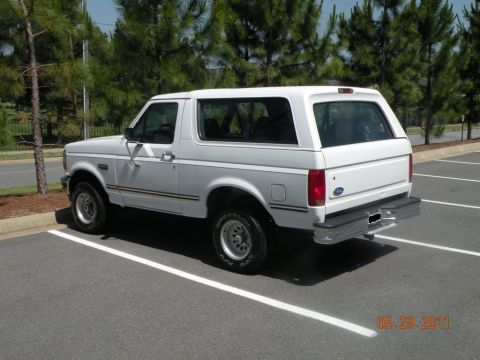 1996 Ford Bronco - A white Ford Bronco is parked in a lot with trees in the background.
