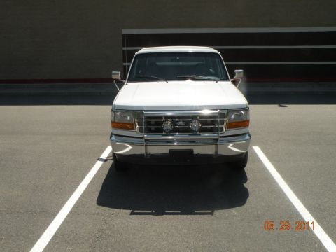 1996 Ford Bronco - A white Ford truck is parked head-on in a parking space, showing its front grille and bumper.