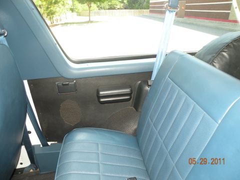 1996 Ford Bronco - Interior view of a vehicle showing blue patterned seats and door panel with a visible seatbelt and a watermark.
