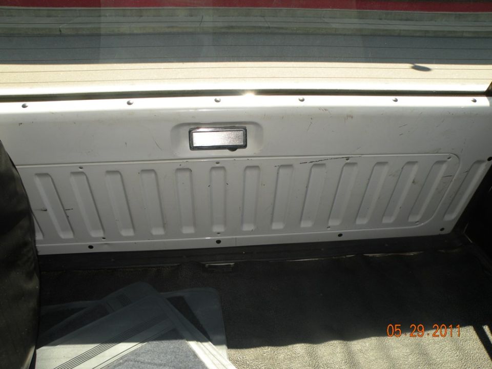 Inside of a white tailgate with a chrome handle and ribbed paneling