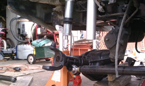 1990 Ford Bronco - Close-up of vehicle suspension components being worked on in a garage setting.