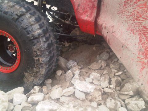 1986 Ford Bronco - Off-road tire and undercarriage detail on rocky terrain.