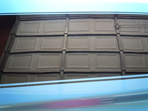 1972 Chevrolet Camaro - A reflection of a blue car is visible on the lower portion of the image, beneath a damaged garage door.