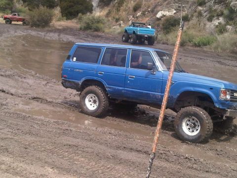 1986 Ford Bronco - Multiple off-road vehicles navigate a muddy trail during an outing.