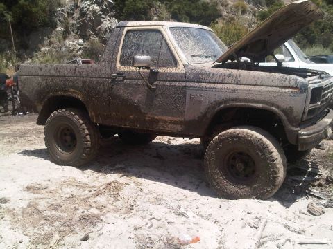1986 Ford Bronco - This off-road vehicle is covered in mud, suggesting it has been used for off-roading.