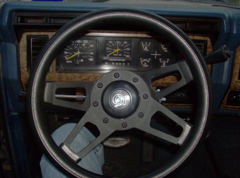 1986 Ford Bronco - The interior of a 1986 Ford Bronco shows a Grant steering wheel and wood-grain trim on the dashboard.