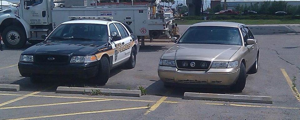 2000 Mercury Grand Marquis parked next to a police sedan