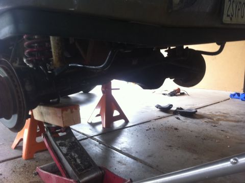 1990 Ford Bronco - The rear axle and suspension components are visible, supported by jack stands and a hydraulic jack.