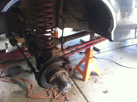 1990 Ford Bronco - Vehicle's front suspension and brake assembly are visible, supported by jack stands.