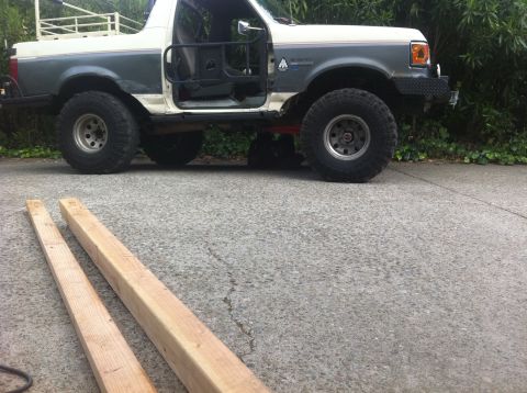 1990 Ford Bronco - Modified Ford Bronco with lifted suspension and off-road tires sits parked on pavement.