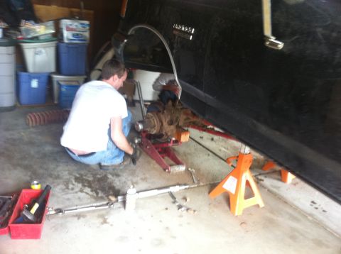 1990 Ford Bronco - A mechanic works on the suspension of a 1990 Ford Bronco in a garage.
