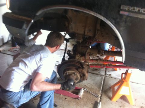 1990 Ford Bronco - Mechanic performing maintenance on the front suspension of a 1990 Ford Bronco.