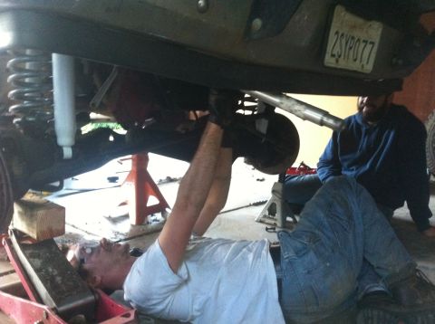 1990 Ford Bronco - Mechanics work on the rear suspension of a lifted 1990 Ford Bronco.