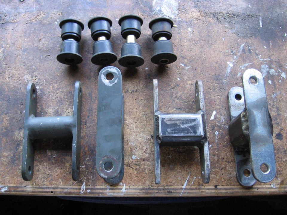 four rubber bushings and four metal suspension links laid out on a workbench
