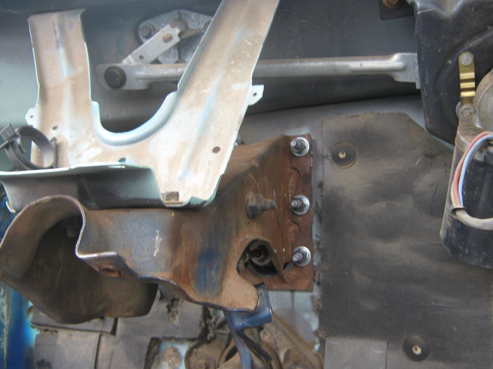 Rusty metal bracket and bolts on a vehicle chassis, with wiper mechanism visible