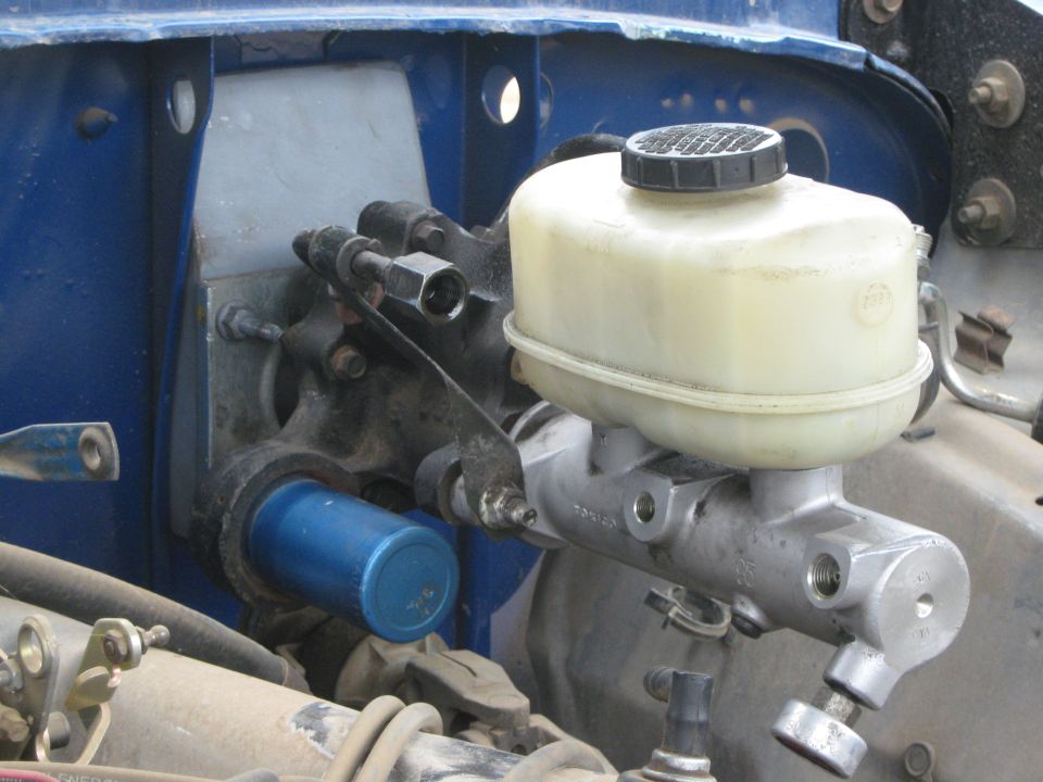 Brake master cylinder assembly with plastic reservoir and black cap. Blue cylinder visible