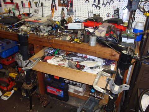 1989 Ford Bronco - A cluttered workbench in a garage, filled with tools and automotive parts.