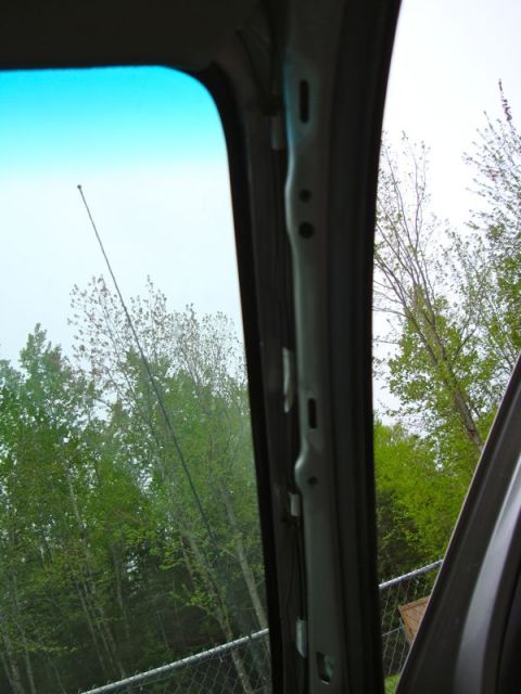 2002 Toyota 4Runner - View from inside a vehicle shows an interior pillar and an antenna against a green, treed background.