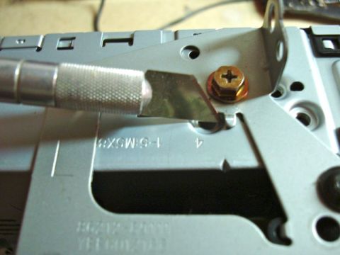 2002 Toyota 4Runner - A utility knife is used to modify a metal bracket during a car stereo installation.