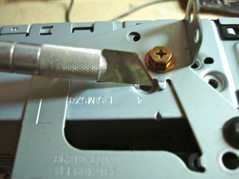 Close-up of a utility knife cutting a metal bracket on a car stereo