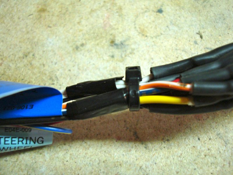 Close-up of a wiring harness with a blue label that says STEERING WHEEL