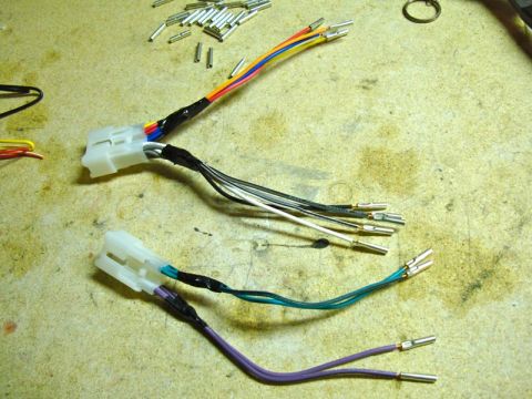 2002 Toyota 4Runner - Two wiring harness adapters are laid out on a workbench with a pile of crimped connectors in the background.