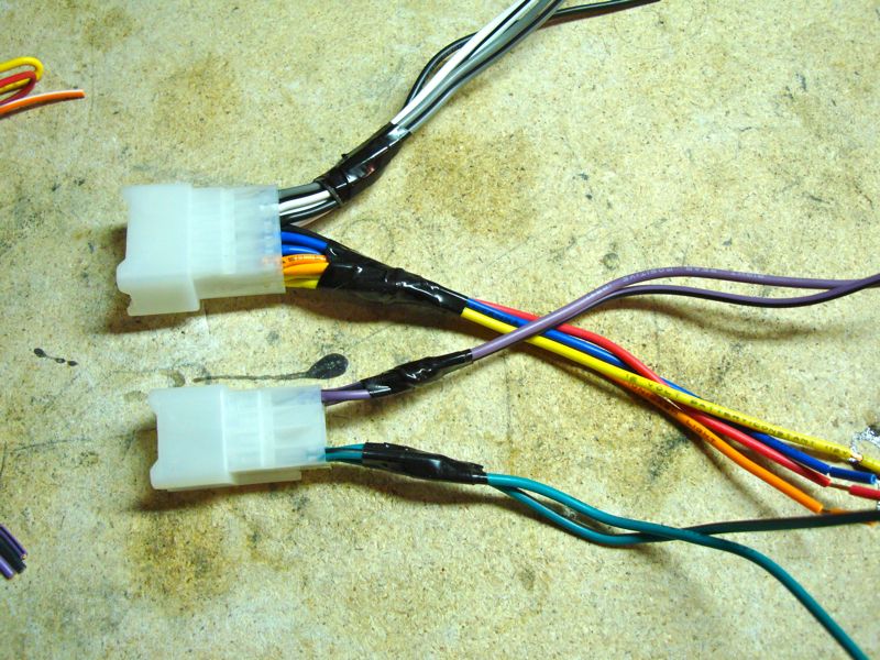 Wiring harness connectors with black tape and colorful wires on a workbench