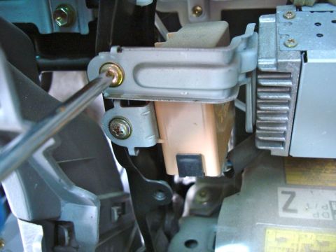 2002 Toyota 4Runner - A screwdriver is used to remove a bracket from the car's dashboard, revealing internal components.