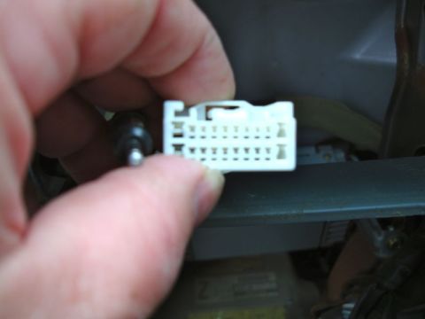 2002 Toyota 4Runner - A hand holds a white wiring harness connector, likely for a car stereo installation.