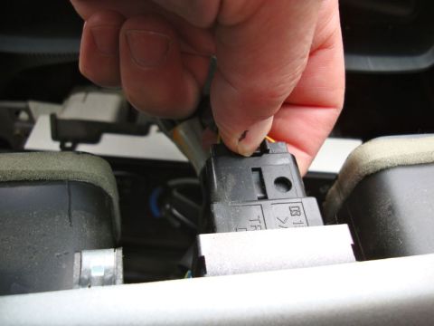 2002 Toyota 4Runner - A hand disconnects a wire harness, likely for a car stereo installation.