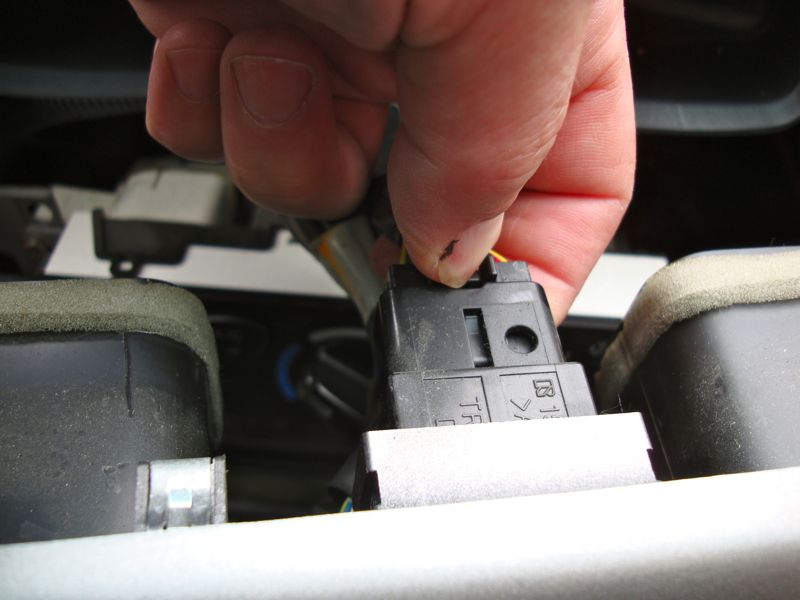 Hand disconnecting black wire harness with yellow wire