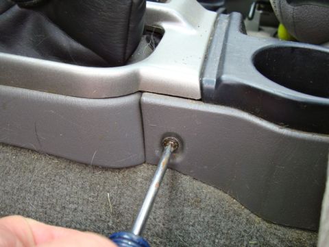 2002 Toyota 4Runner - A screwdriver is used to remove a screw from the interior trim panel of a vehicle's center console.