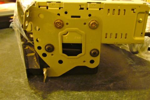 2002 Toyota 4Runner - Close-up of a yellow car stereo mounting bracket, showing screws and ventilation slots.