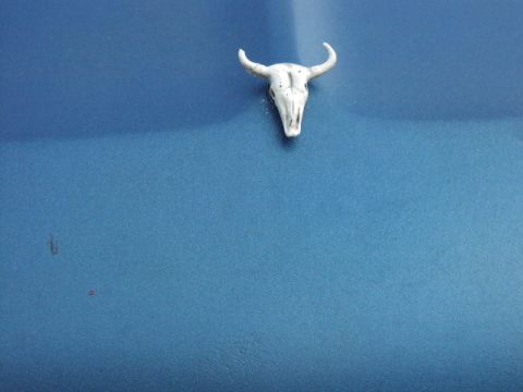 1981 Ford Bronco - Bull skull emblem attached to a blue surface, possibly a vehicle panel.