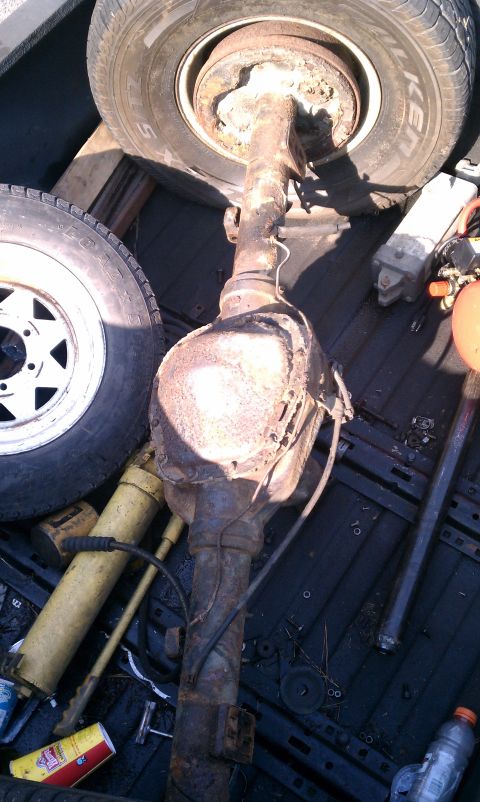 1990 Ford Bronco - A rear axle assembly is shown with two tires and a yellow grease gun in the background.