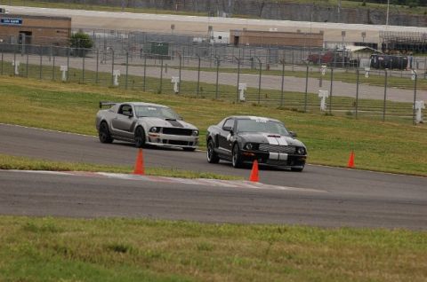 2007 Ford Mustang - Two 2007 Ford Mustangs compete on a race track, their aggressive styling and performance capabilities.