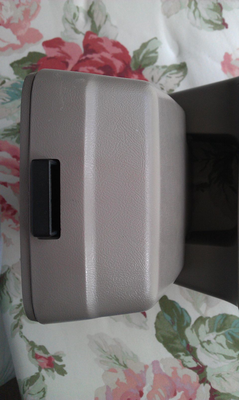 Tan plastic interior storage bin or ashtray on a floral fabric surface