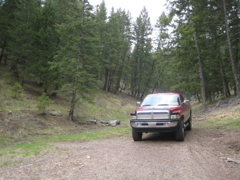 1997 Dodge 2500 - A red 1997 Dodge 2500 pickup truck is parked on a gravel road surrounded by pine trees.