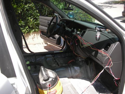 2004 Ford Crown Victoria - Interior of a 2004 Ford Crown Victoria undergoing modifications, showing exposed wiring and a shop vac.