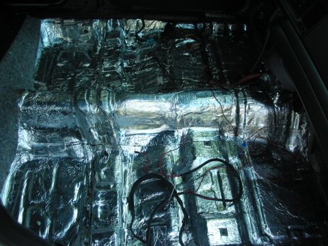 2004 Ford Crown Victoria - The interior floor of a vehicle is covered in sound deadening material with wiring visible.
